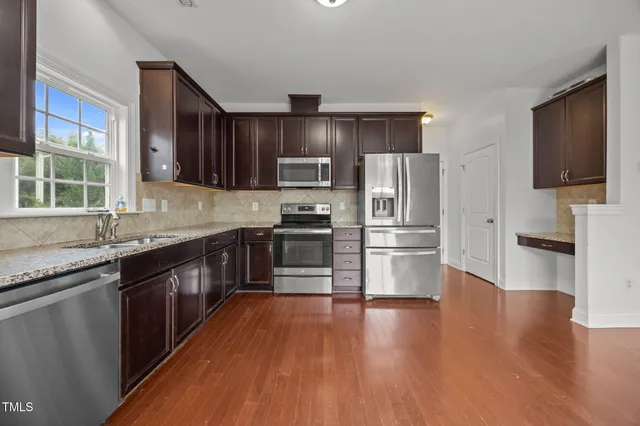 a kitchen with stainless steel appliances wooden floors and wooden cabinets