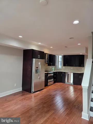 a living room with stainless steel appliances furniture and a kitchen