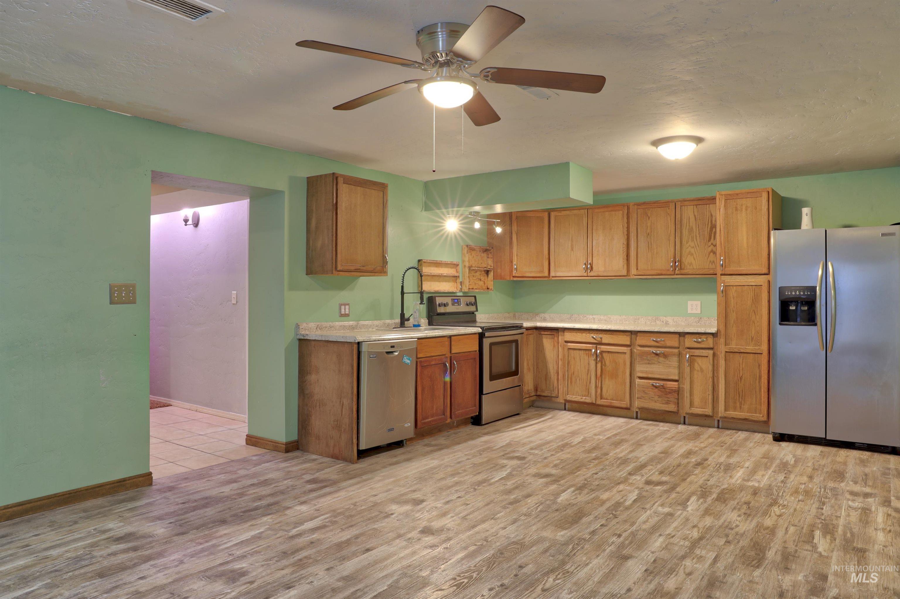 526 Ridge Drive Nampa, ID 83686 - Photo 17 of 21 Kitchen featuring appliances with stainless steel finishes, light countertops, brown cabinets, a ceiling fan, and a textured ceiling