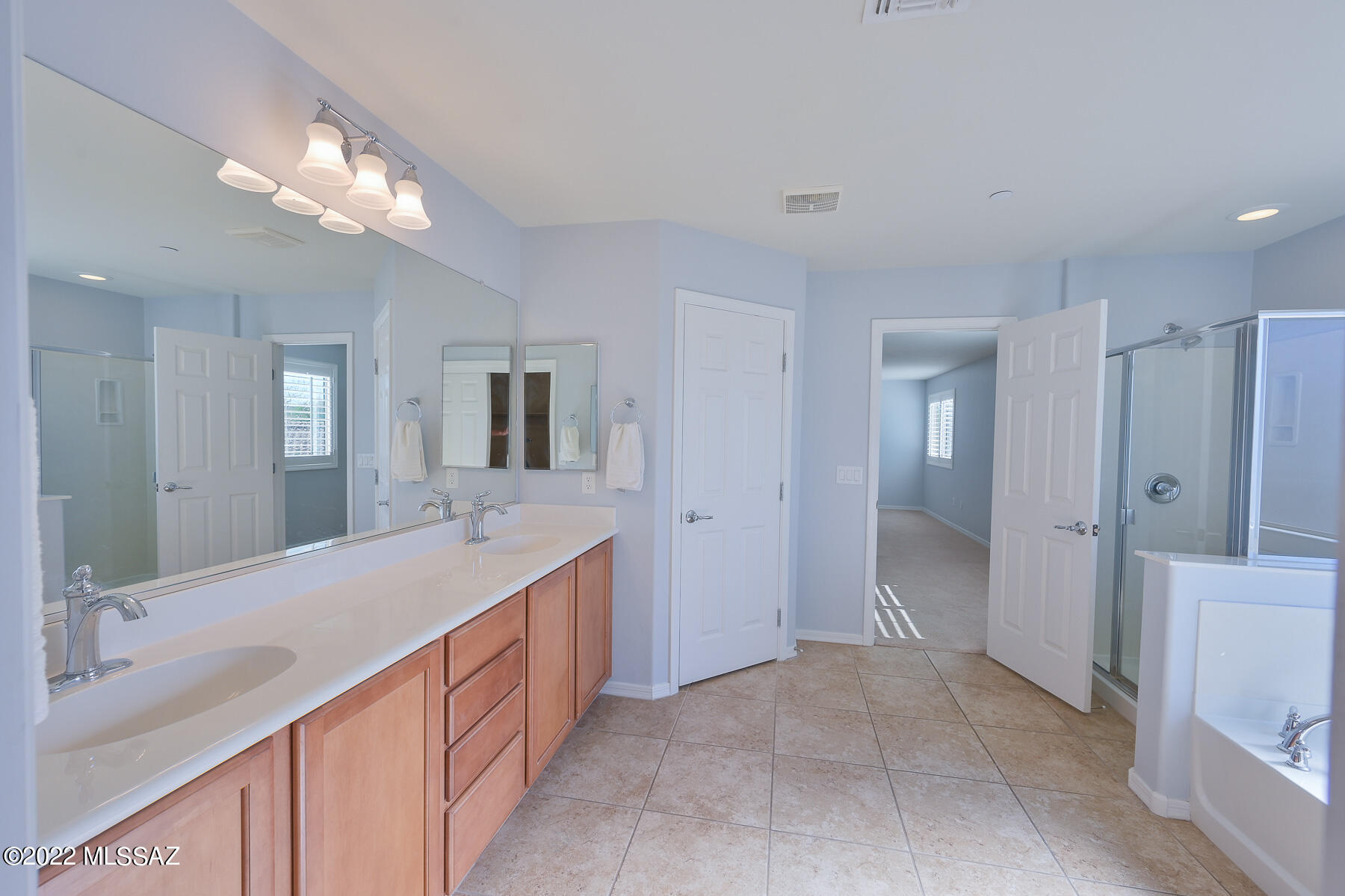 10804 East Salsabila Road Tucson, AZ 85747 - Photo 31 of 50 a spacious bathroom with a double vanity sink a large mirror and a shower