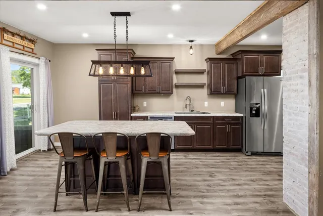 a kitchen with stainless steel appliances a dining table chairs refrigerator and cabinets