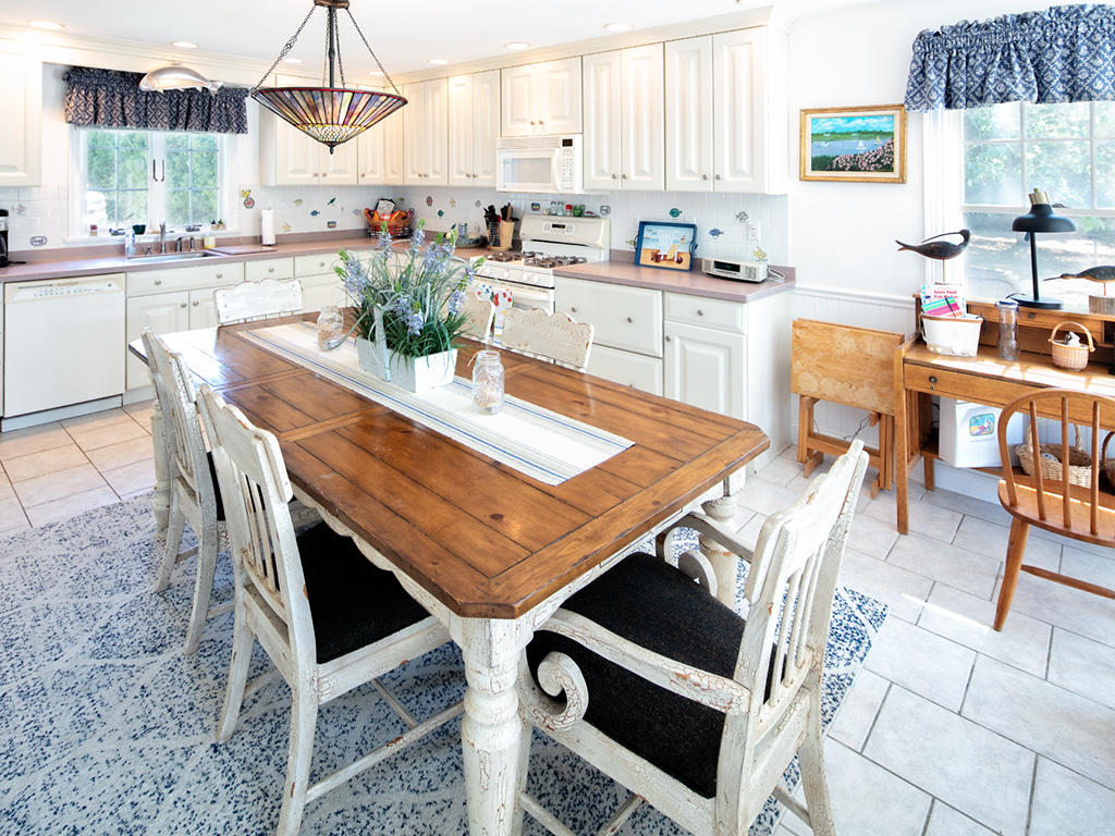 409 Monomoscoy Road Mashpee, MA 02649 - Photo 9 of 16 a kitchen with stainless steel appliances kitchen island granite countertop a table chairs and a refrigerator