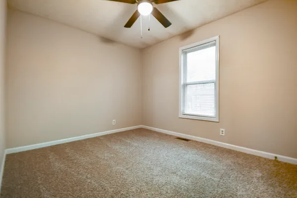 an empty room with a window and ceiling fan