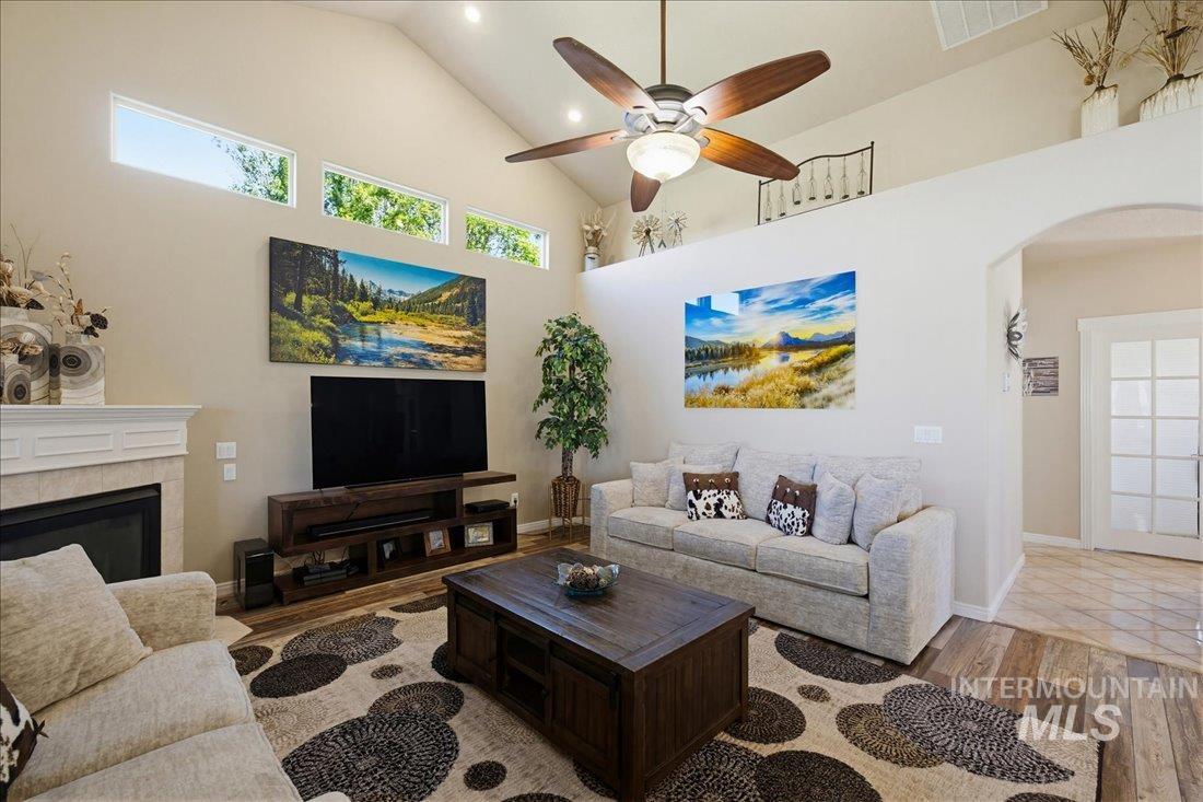 24623 Falcon Lane Caldwell, ID 83607 - Photo 7 of 40 Vaulted ceilings featuring recessed lighting and a ceiling fan, a fireplace with a white mantel, high transom windows, wood-finish flooring, and an arched doorway