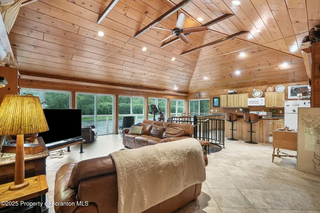 a living room with furniture a flat screen tv and a floor to ceiling window
