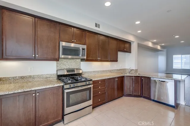 a kitchen with stainless steel appliances granite countertop wooden cabinets and a stove top oven