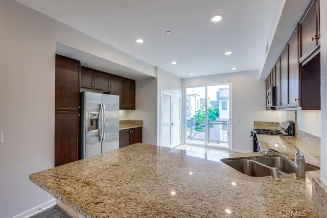 a kitchen with stainless steel appliances kitchen island granite countertop a sink and a refrigerator