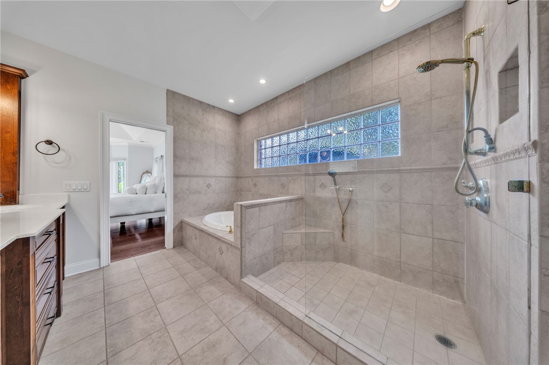 102 Country Walk Lane Clemson, SC 29631 - Photo 19 of 39 Luxurious tiled bathroom retreat features a spacious walk-in shower and soaking tub, with warm wooden vanity.