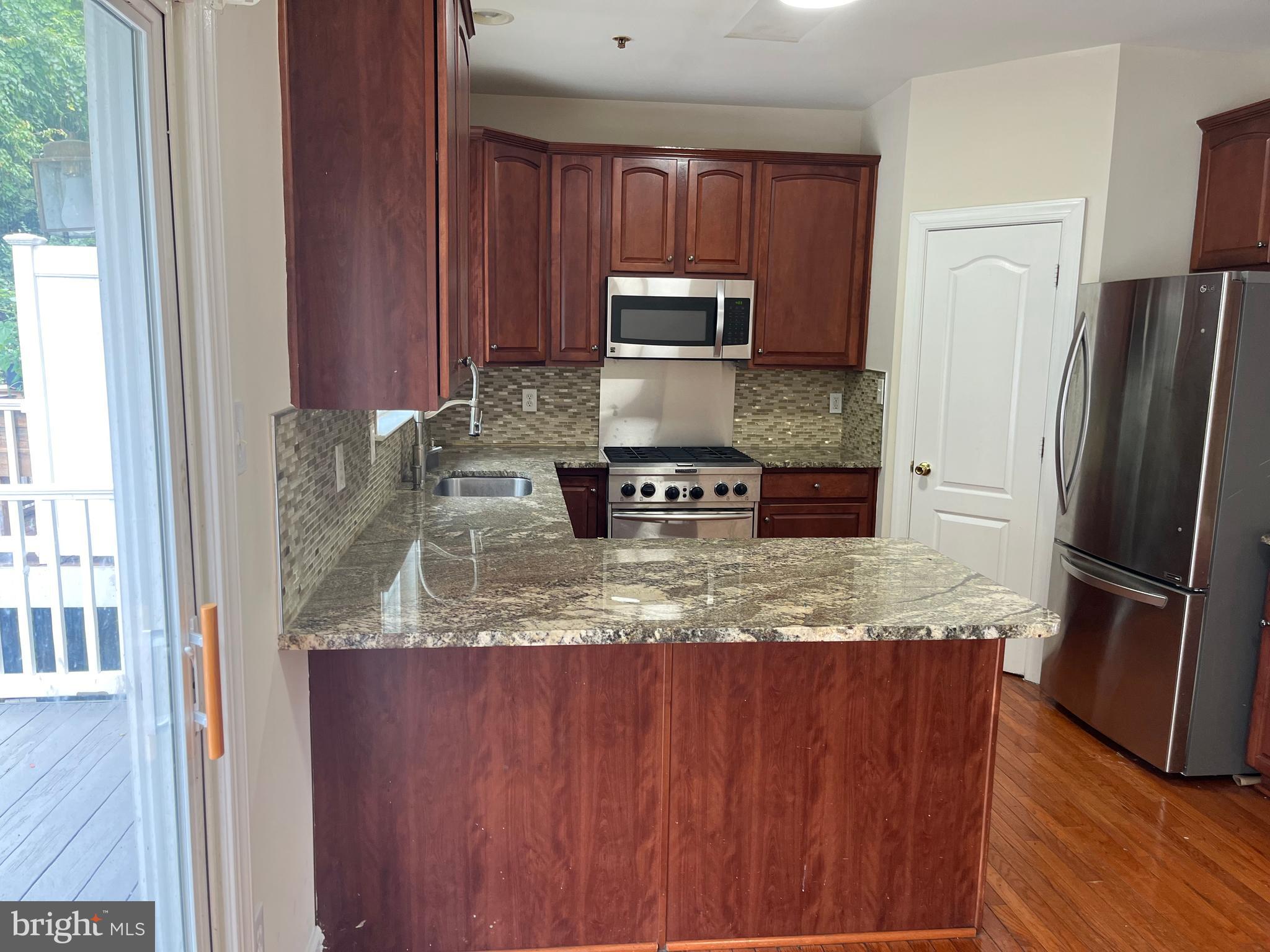3316 Castle Ridge Circle, Unit 16 Silver Spring, MD 20904 - Photo 24 of 71 a kitchen with stainless steel appliances granite countertop a refrigerator a stove and a sink with wooden cabinets