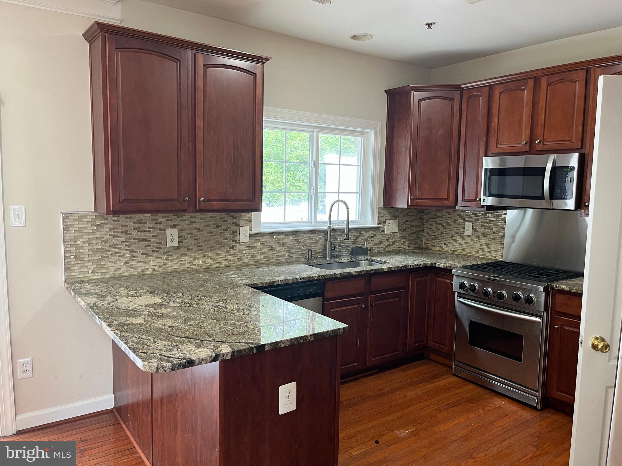 3316 Castle Ridge Circle, Unit 16 Silver Spring, MD 20904 - Photo 30 of 71 a kitchen with granite countertop wooden cabinets a stove top oven and granite counter tops