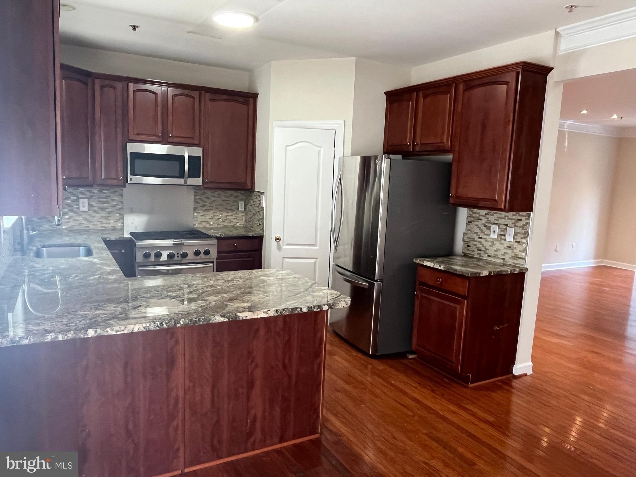 3316 Castle Ridge Circle, Unit 16 Silver Spring, MD 20904 - Photo 38 of 71 a kitchen with granite countertop wooden cabinets a refrigerator and a sink