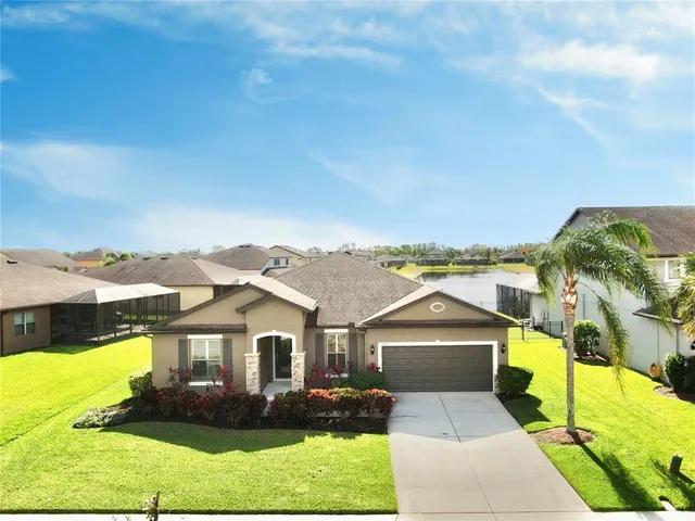 a front view of a house with a yard and potted plants
