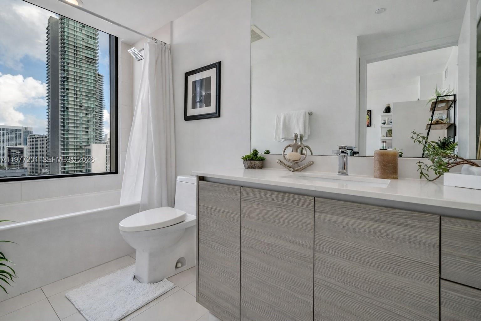 460 Northeast 28th Street, Unit 1901 Miami, FL 33137 - Photo 23 of 31 a bathroom with a sink a toilet a large mirror and shower