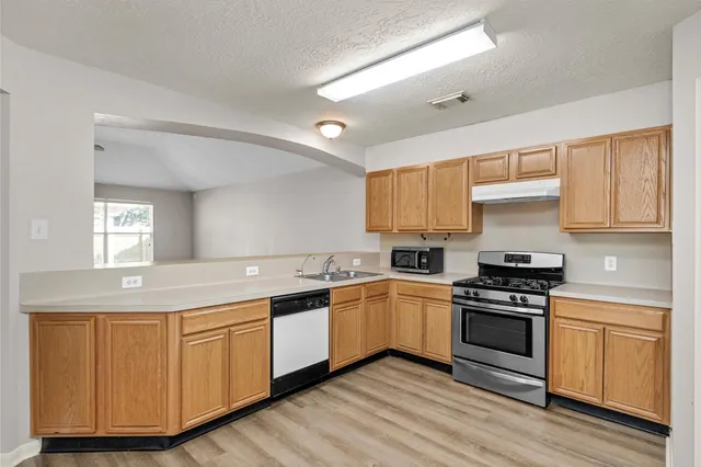 a kitchen with white cabinets appliances and wooden floor