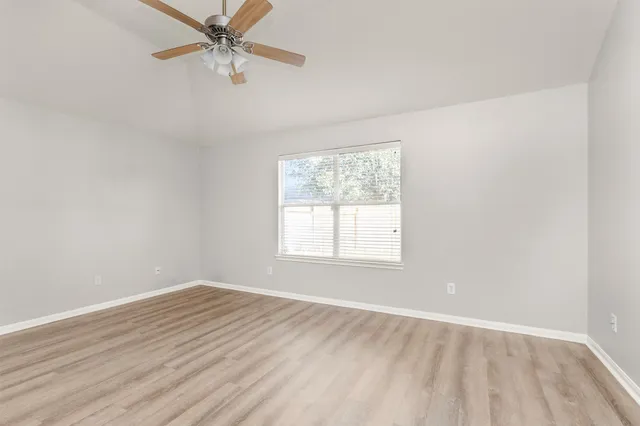 an empty room with a window and ceiling fan