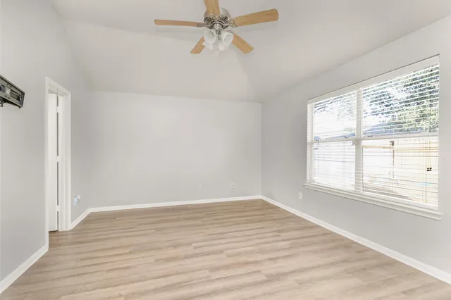 an empty room with wooden floor fan and windows