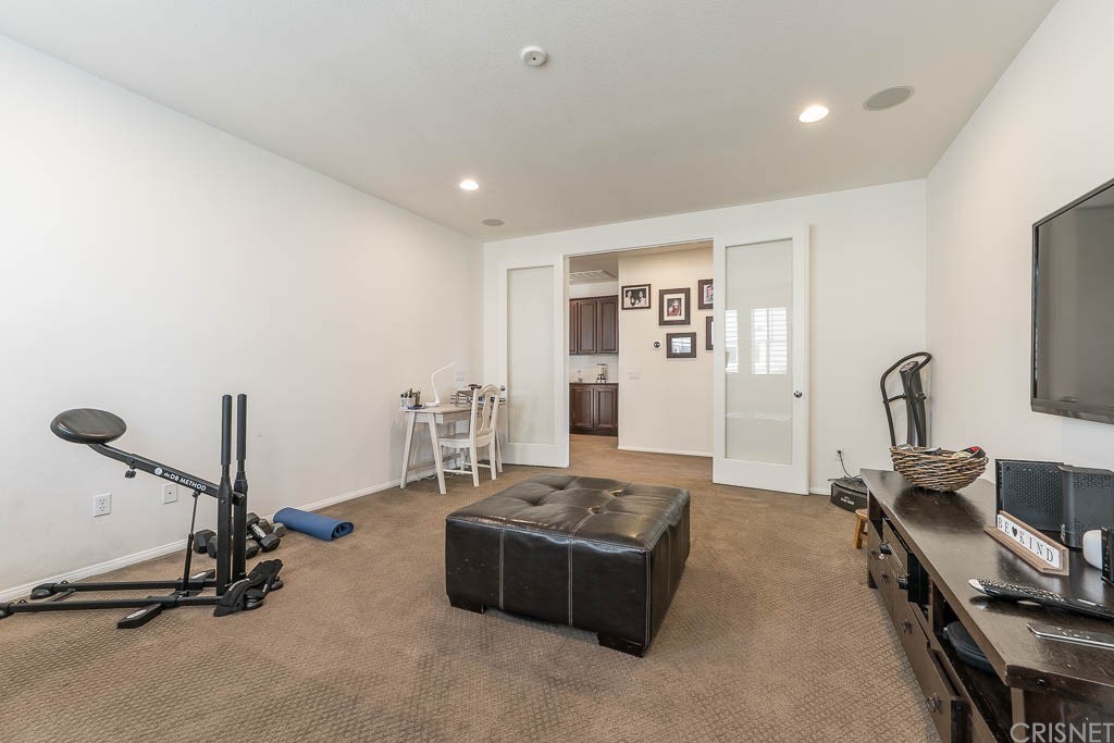 11564 Apulia Court Porter Ranch, CA 91326 - Photo 29 of 72 a living room with furniture gym equipment and a floor to ceiling window