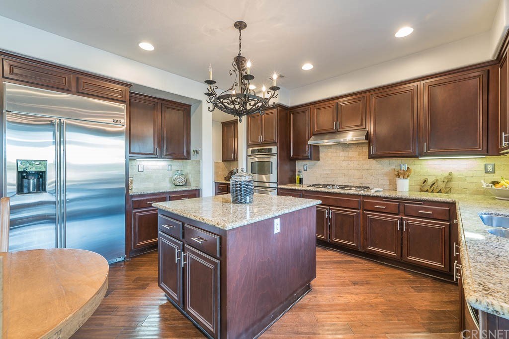 11564 Apulia Court Porter Ranch, CA 91326 - Photo 5 of 72 a kitchen with kitchen island granite countertop a sink stove and cabinets