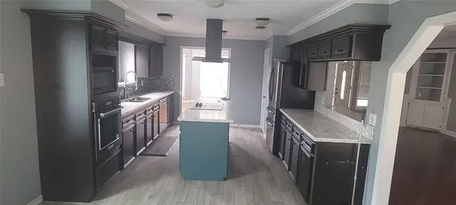 a kitchen with granite countertop a refrigerator a sink and wooden floors