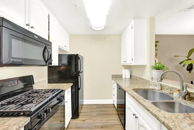 a kitchen with granite countertop a stove sink and cabinets