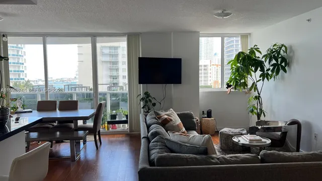 a living room with furniture floor to ceiling window and a flat screen tv