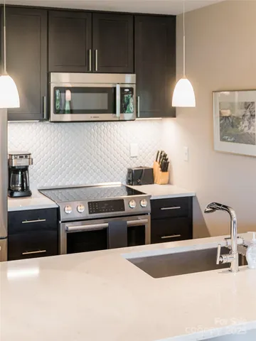 a kitchen with stainless steel appliances granite countertop a stove a sink and a microwave