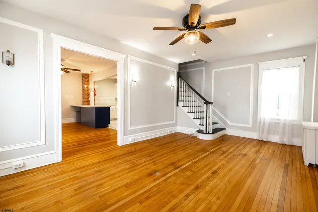a view of empty room with wooden floor and fan