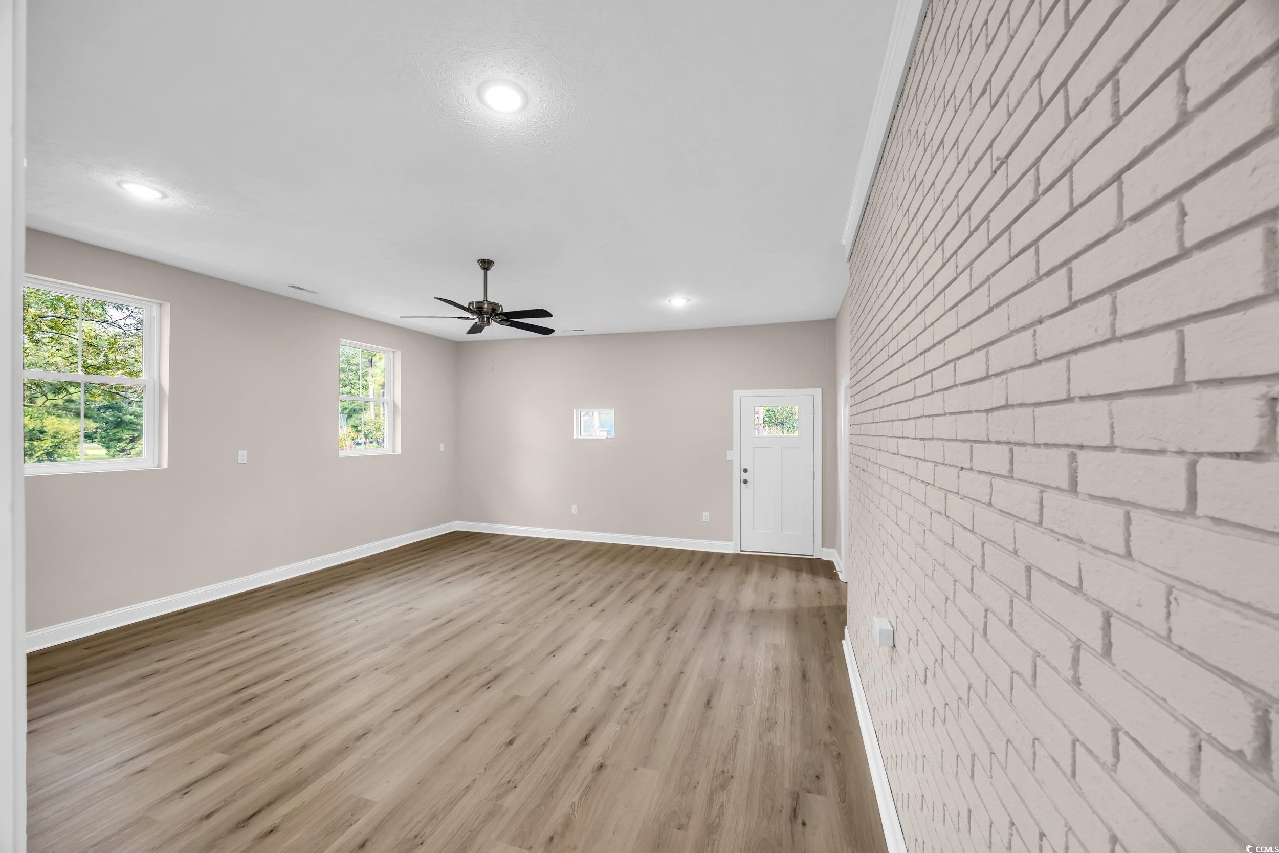 970 Virginia Drive Loris, SC 29569 - Photo 10 of 28 Unfurnished living room featuring brick wall, light wood finished floors, plenty of natural light, recessed lighting, and a ceiling fan