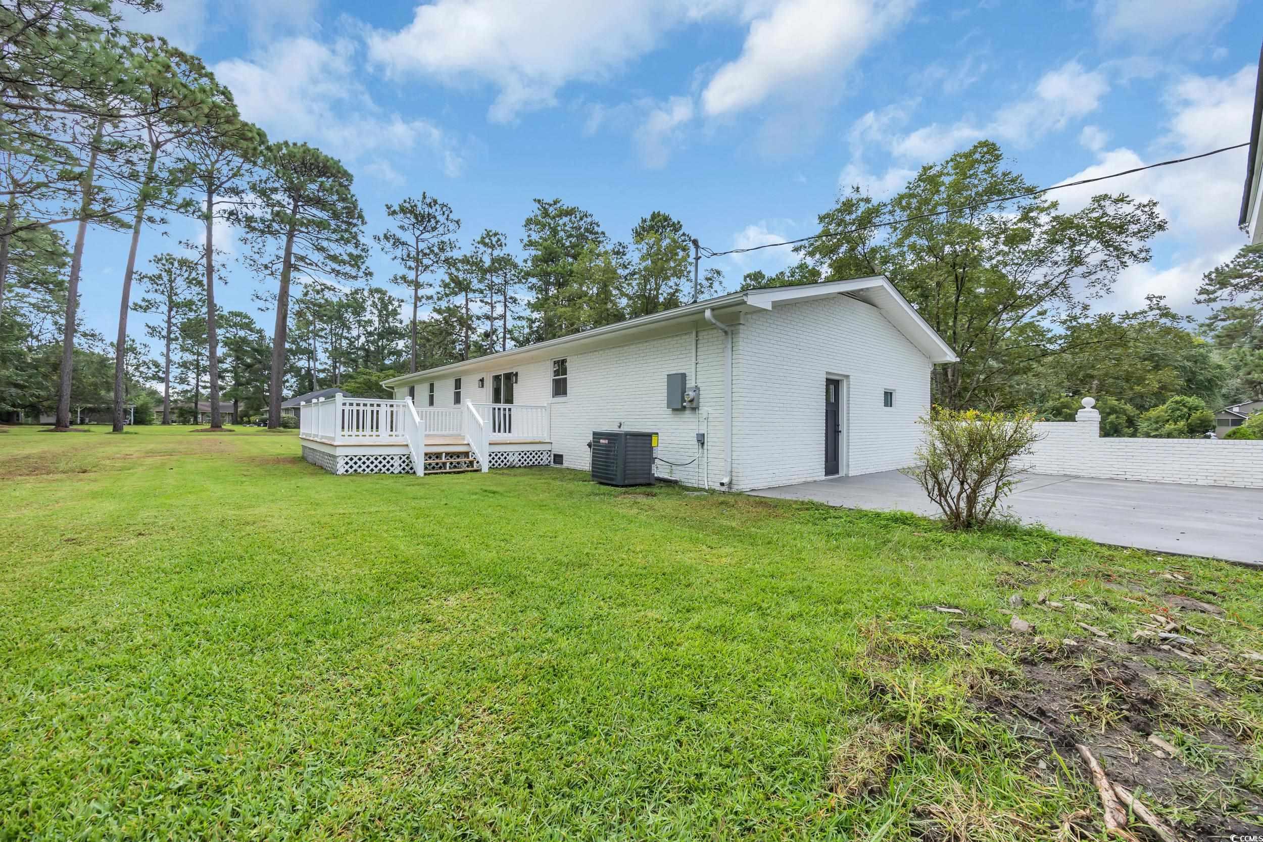 970 Virginia Drive Loris, SC 29569 - Photo 22 of 28 Rear view of house with a yard, a wooden deck, brick siding, concrete driveway, and a patio