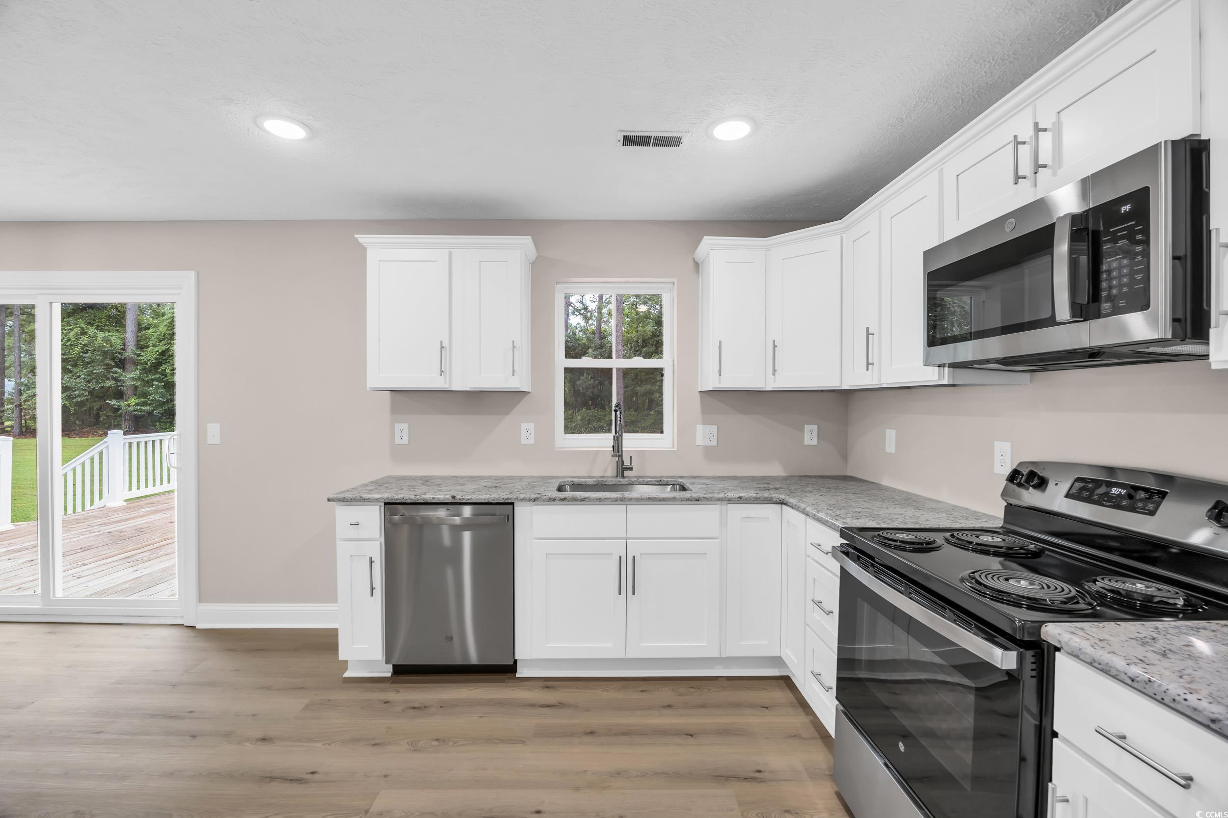 970 Virginia Drive Loris, SC 29569 - Photo 9 of 28 Kitchen with appliances with stainless steel finishes, white cabinets, light wood-type flooring, recessed lighting, and light stone countertops