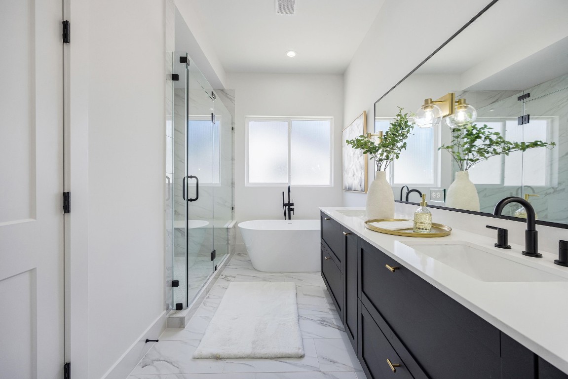 303 Marcella Street, Unit P Houston, TX 77091 - Photo 4 of 26 Luxurious primary bath featuring elegant marble finishes, a spacious glass-enclosed shower, a freestanding luxurious tub, and a double vanity with ample storage.