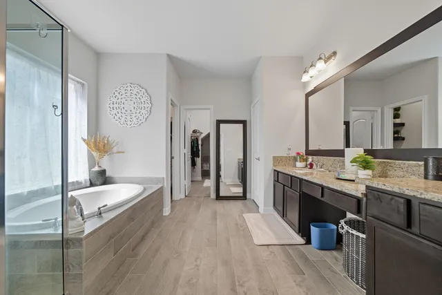 a large bathroom with a granite countertop double vanity sink a mirror and a shower