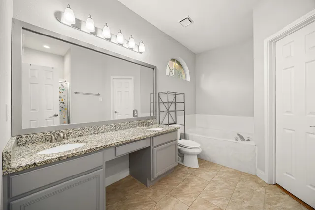 a bathroom with a granite countertop sink a toilet and a mirror