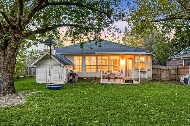 a large tree in front of a house with a yard and porch