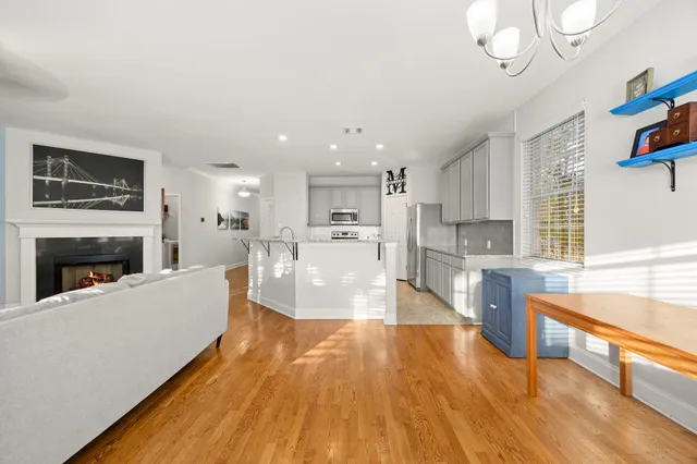 a living room with stainless steel appliances granite countertop a couch a fireplace a flat screen tv and a fireplace