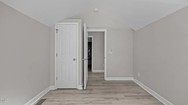 a view of an empty room with wooden floor and closet