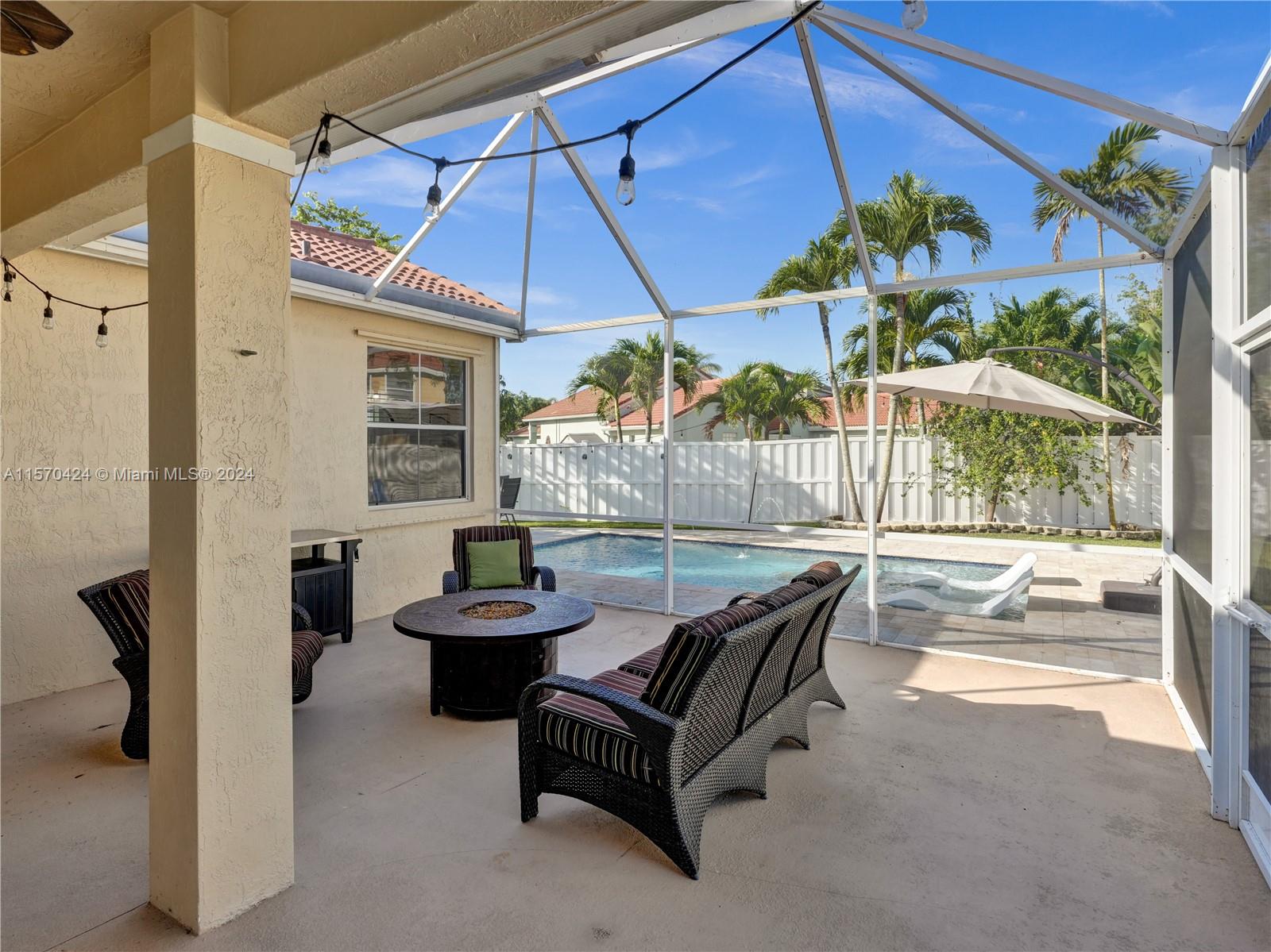 849 Falling Water Road Weston, FL 33326 - Photo 17 of 25 a outdoor living space with furniture and umbrella