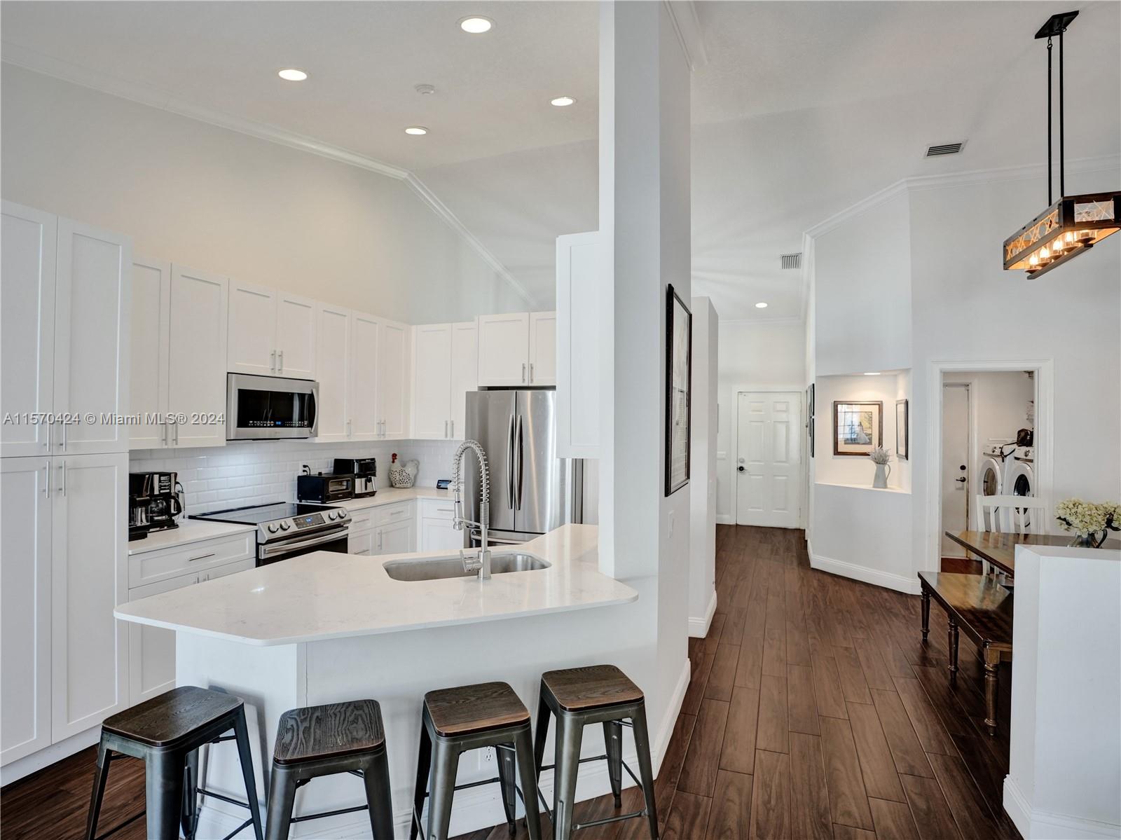 849 Falling Water Road Weston, FL 33326 - Photo 7 of 25 a kitchen with stainless steel appliances a sink a stove a refrigerator cabinets and a dining table