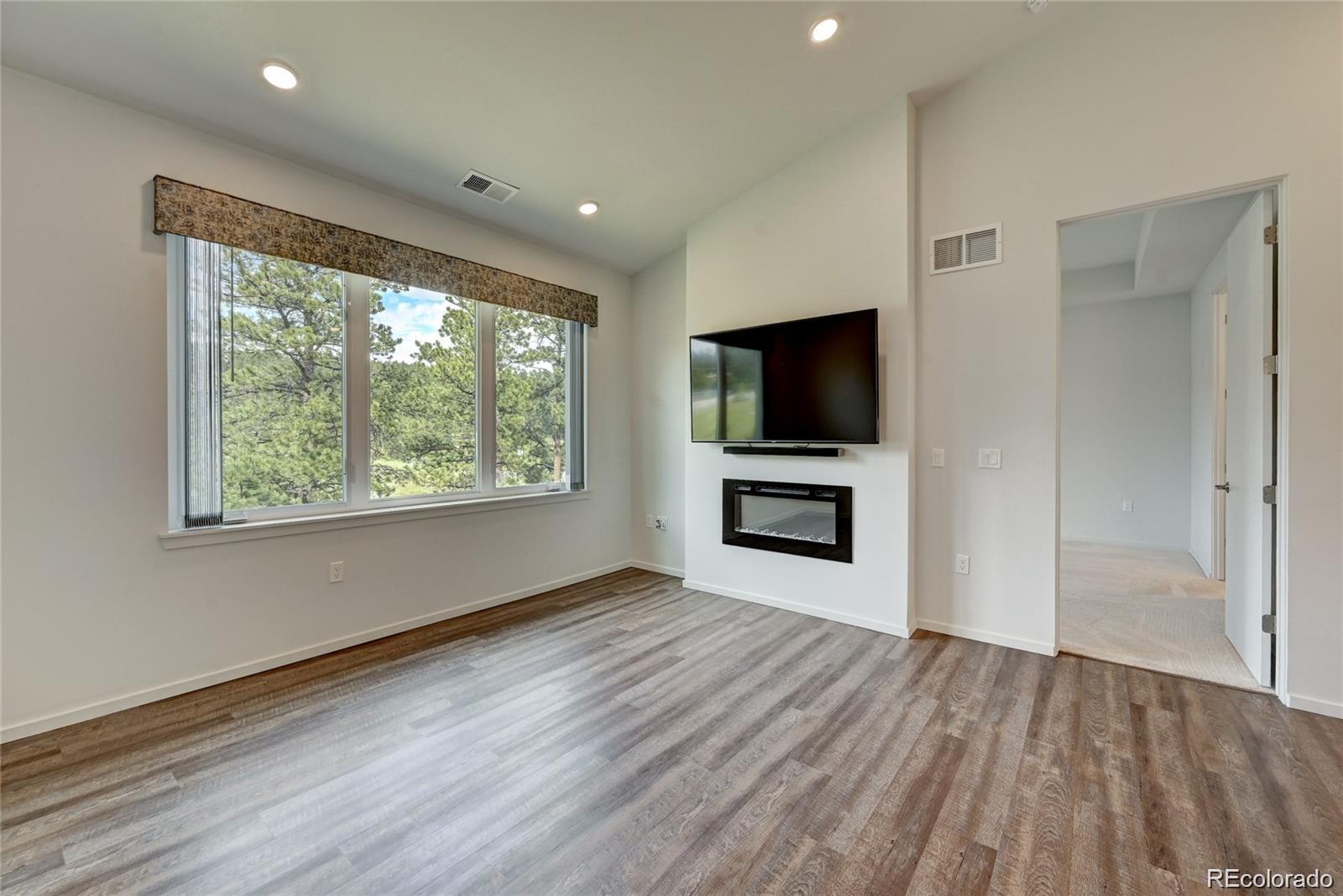 31191 Black Eagle Drive, Unit 301 Evergreen, CO 80439 - Photo 13 of 35 a view of a livingroom with wooden floor a flat screen tv and staircase