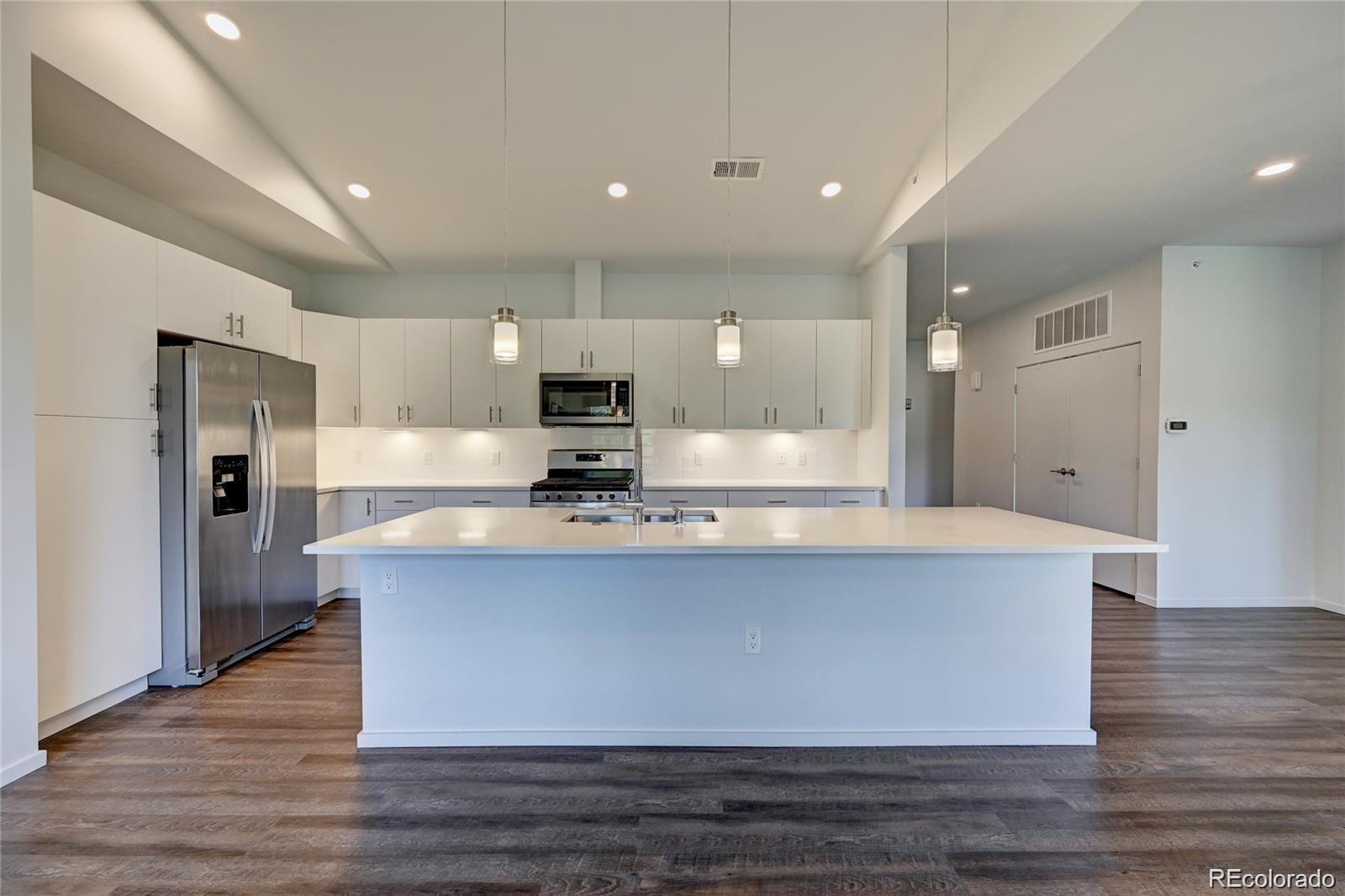 31191 Black Eagle Drive, Unit 301 Evergreen, CO 80439 - Photo 7 of 35 a large kitchen with stainless steel appliances a large counter top a stove and a refrigerator