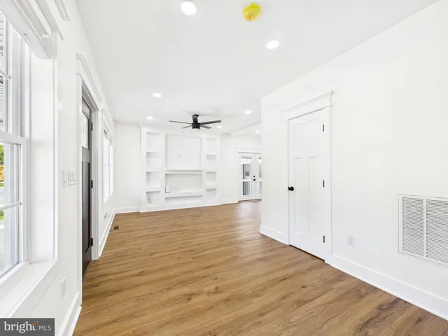 an empty room with wooden floor and ceiling fan