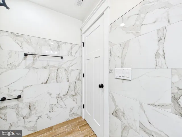 a view of an empty room with wooden floor and a ceiling fan