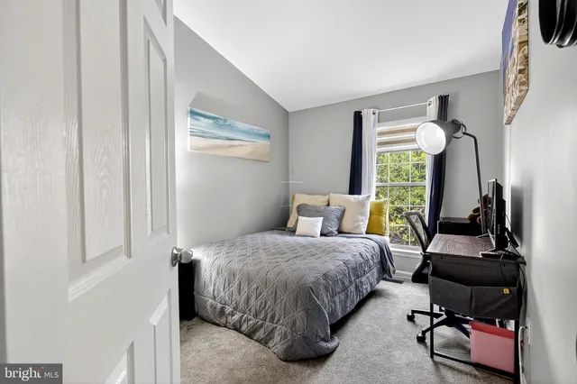 a bedroom with a bed a computer on the desk and a window