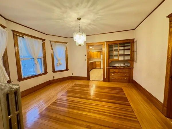 a view of an empty room with a fireplace and wooden floor