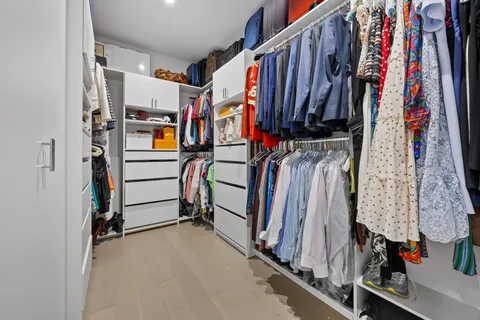 a view of walk in closet with clothes and shoes