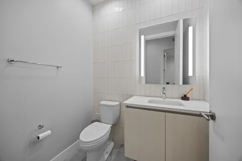 a bathroom with a toilet sink vanity and mirror