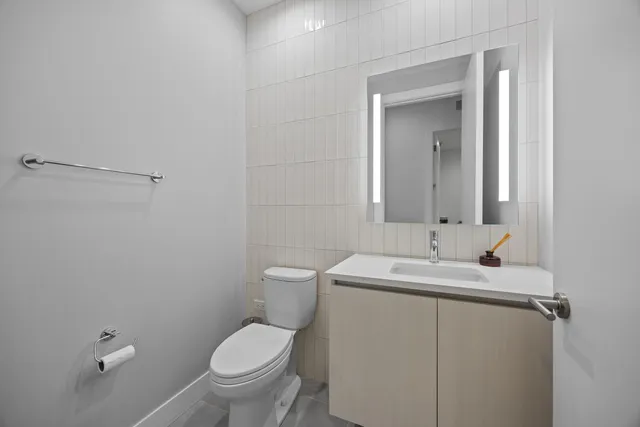 a bathroom with a toilet sink vanity and mirror