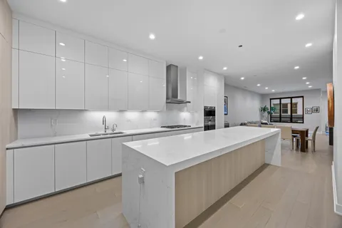 a large white kitchen with kitchen island a sink a stove a center island and furniture