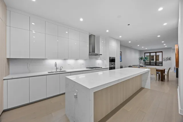 a large white kitchen with kitchen island a sink a stove a center island and furniture