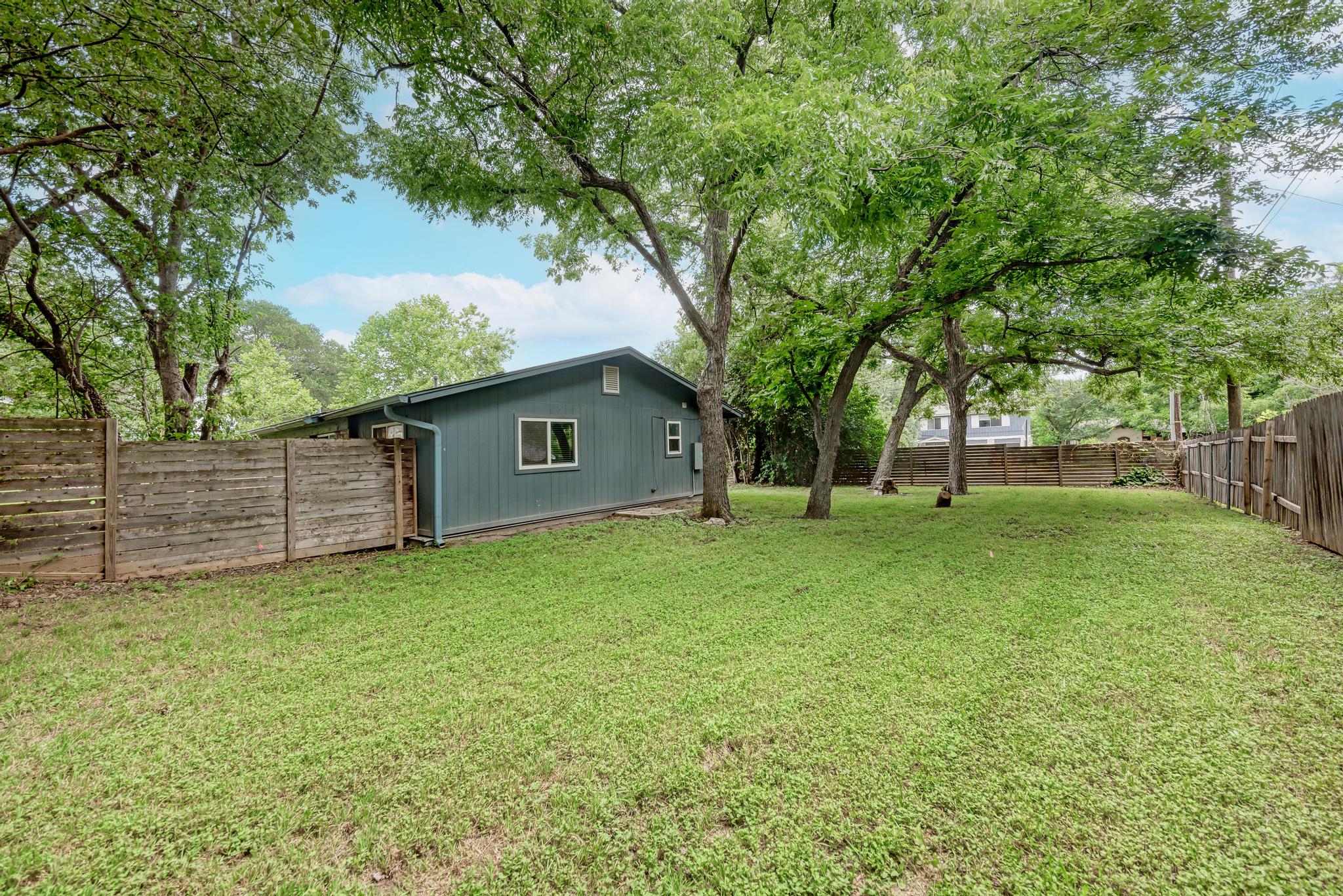 6700 Kings Point Austin, TX 78723 - Photo 40 of 40 A spacious yard with mature trees and privacy fencing, perfect for outdoor activities.